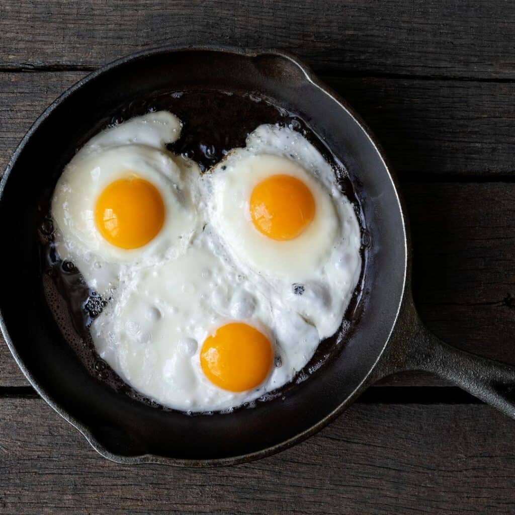 three fried eggs in a cast iron skillet